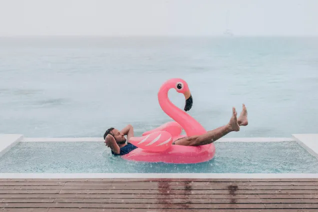 man relaxing in pool flamingo in the rain 